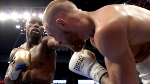 Floyd Mayweather (left) throws a punch at Conor McGregor (right) during their super welterweight boxing match. (Getty)