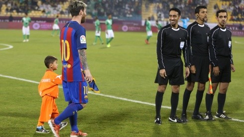 Afghan boy Murtaza Amadi walks with Lionel Messi of Barcelona in 2016. (Getty)