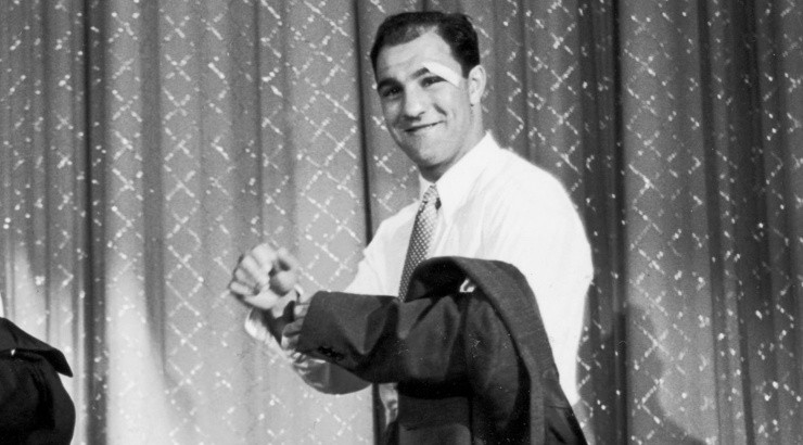 Rocky Marciano removes their jackets on stage during a variety show during the 1950s. (Getty)