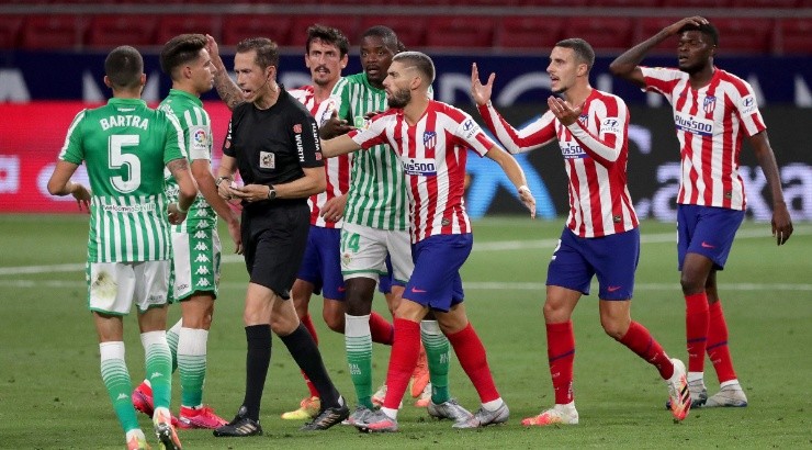 Atletico Madrid and Real Betis players gather around the referee after a red card. (Getty)