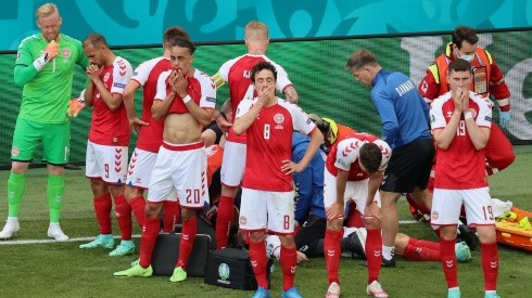 Denmark players look dejected whilst Christian Eriksen receives medical treatment. (Getty)