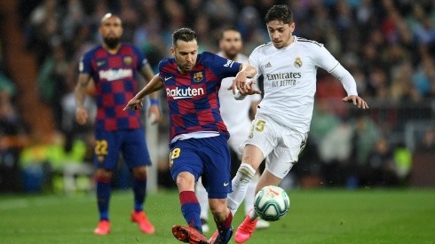 Jordi Alba of FC Barcelona passes the ball under pressure from Federico Valverde of Real Madrid