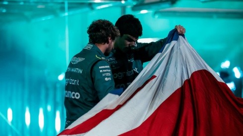 Foto oficial Aston Martin - Vettel e Stroll olhando o carro por baixo da bandeira da Grã-Bretanha