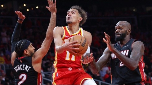 Trae Young of the Atlanta Hawks goes up for a layup against Gabe Vincent and Dewayne Dedmon of the Miami Heat