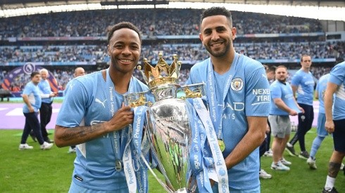 Raheem Sterling and Riyad Mahrez of Manchester City celebrate with the Premier League trophy after their side finished the season as Premier League champions during the Premier League match between Manchester City and Aston Villa at Etihad Stadium on May 22, 2022 in Manchester, England.