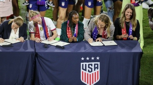 Becky Sauerbrunn y directivos de US Soccer firmando acuerdo