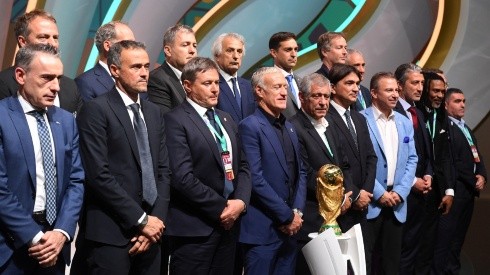 Managers of the national teams at Qatar 2022 pose with the FIFA World Cup trophy.