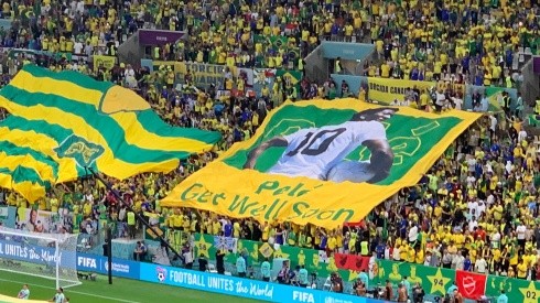 Créditos: Bolavip - Bandeira erguida pela torcida brasileira em homenagem a Pelé antes da partida contra Camarões, no Estádio Nacional de Lusail, em 02/12/2022