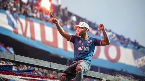 A fan with a flare wears a mask of Luis Suarez during the unveiling of the Uruguayan player Luis Suarez as the new player of Nacional at the Parque Central Stadium on July 31, 2022 in Montevideo, Uruguay.