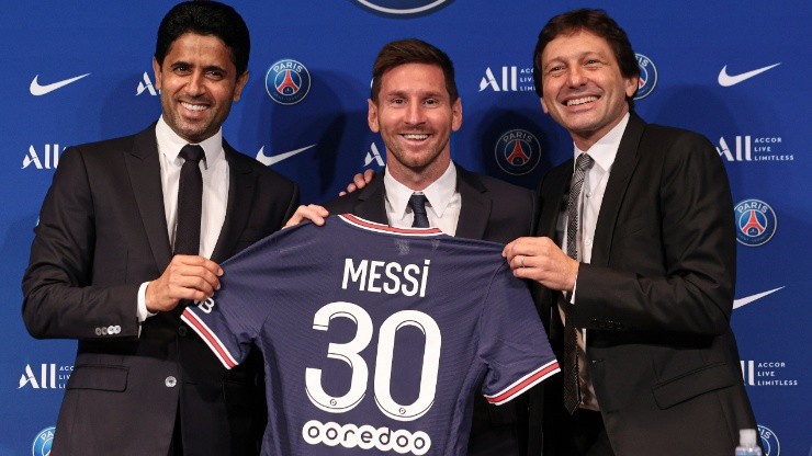 Lionel Messi poses with his jersey next to President Nasser Al Khelaifi and Leonardo