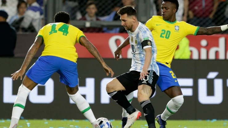Lionel Messi of Argentina competes for the ball with Eder Militão (L) and Vinicius Junior (R) of Brazil