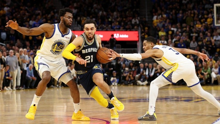 Tyus Jones #21 of the Memphis Grizzlies is covered by Andrew Wiggins #22 and Jordan Poole #3 of the Golden State Warriors