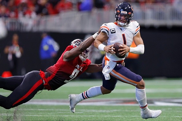 Fields evitando um tackle contra o Falcons. Créditos: Todd Kirkland/Getty Images