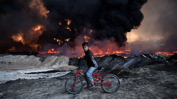 Un niño pasea por su bicicleta en medio de un campo de batalla (Getty Images)
